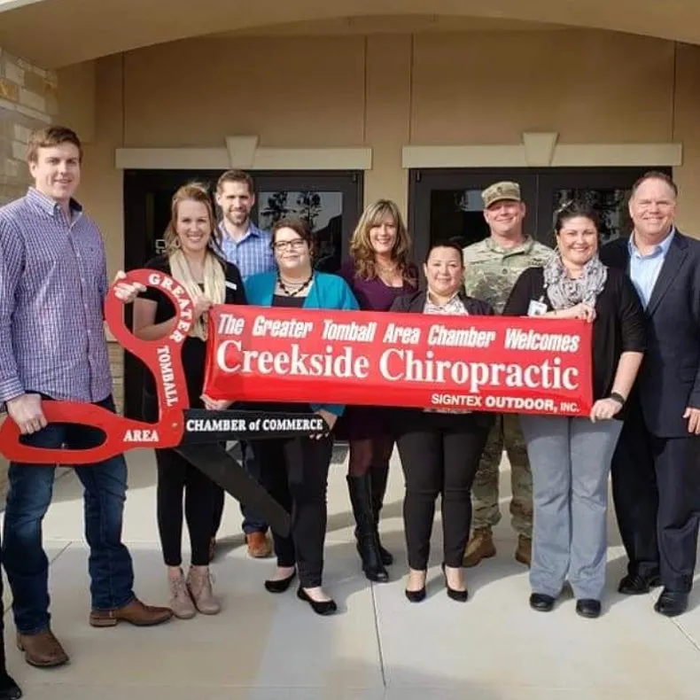 Ribbon cutting ceremony with team and chamber of commerce – Burleson Chiropractic Group photo of Creekside Chiropractic team and chamber of commerce at ribbon cutting event holding giant key – Burleson Chiropractic